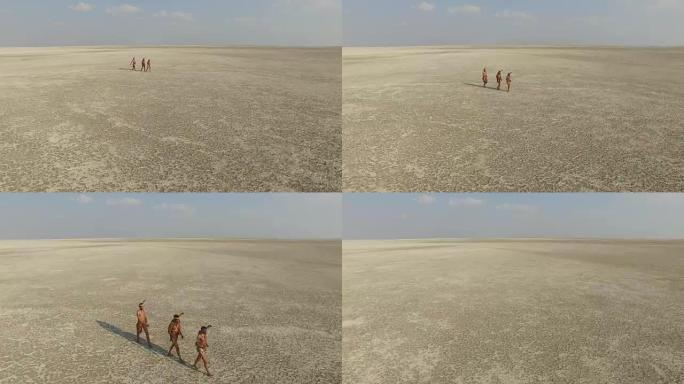 鸟瞰图，三个布希曼人走过广阔的Makgadikgadi pan，博茨瓦纳