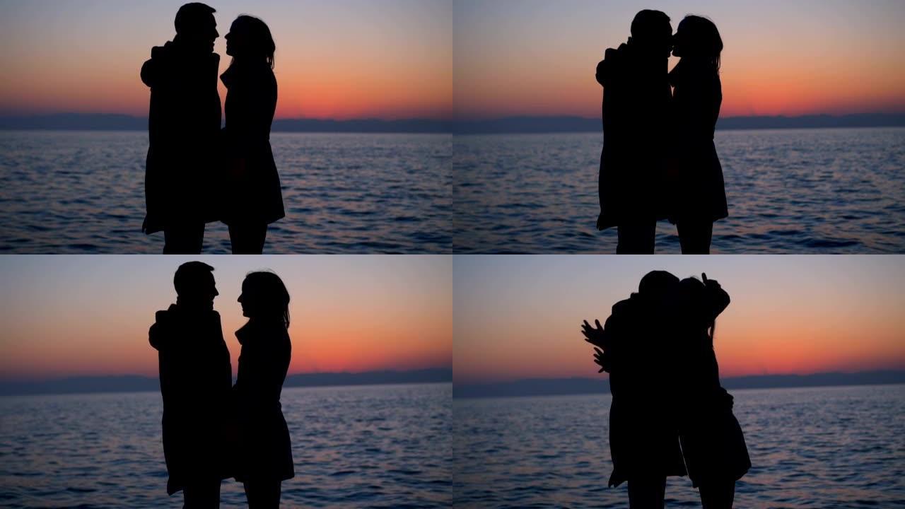 日落中浪漫情侣接吻的剪影