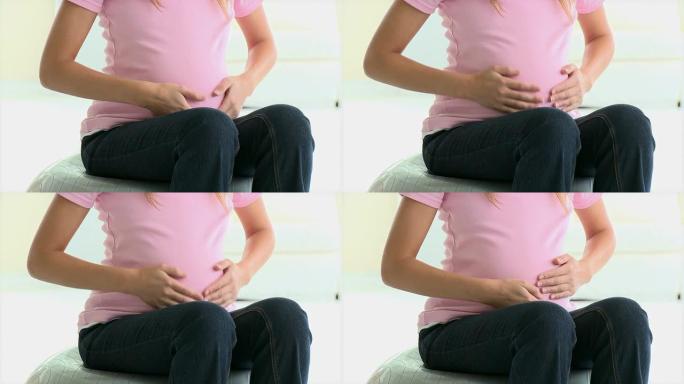 一名孕妇坐着触摸腹部的特写镜头