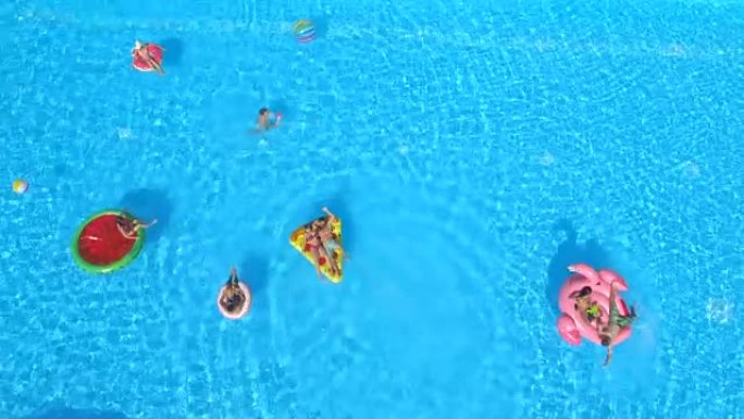 天线: 快乐的人们在泳池水中五颜六色的漂浮物上享受暑假