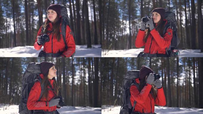 微笑快乐的年轻女子在冬季森林徒步旅行用照相机拍照。