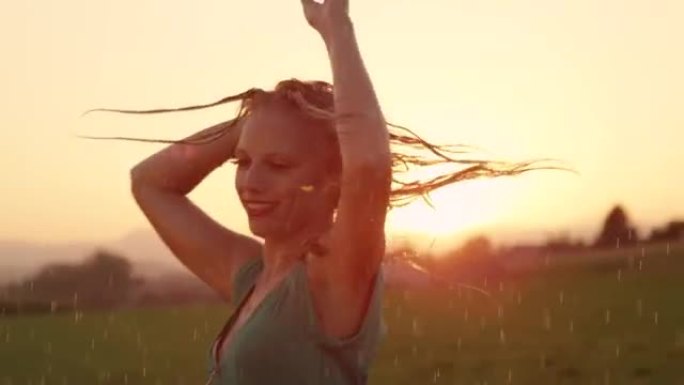 肖像: 无忧无虑的金发女人在日落时在新鲜的雨中在户外跳舞。