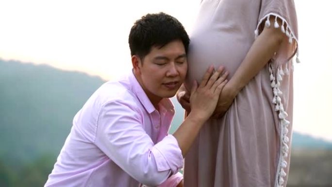 亚洲怀孕夫妇在大自然中抚摸和倾听肚子