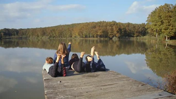 男孩和女孩朋友放松，在宁静的湖码头踢脚，实时