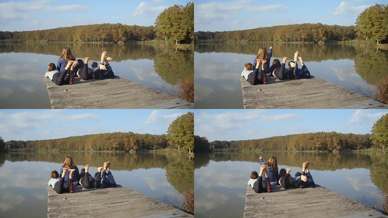 男孩和女孩朋友放松，在宁静的湖码头踢脚，实时