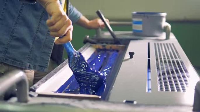 男性工人用刷子在机器的特殊区域甚至连一层蓝色油漆。4K。
