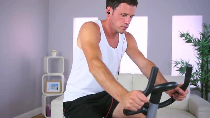 男子在健身车上训练并听音乐