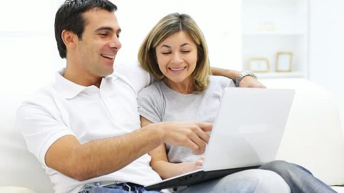 一对夫妇坐在家里用笔记本电脑。
