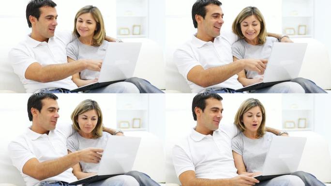 一对夫妇坐在家里用笔记本电脑。