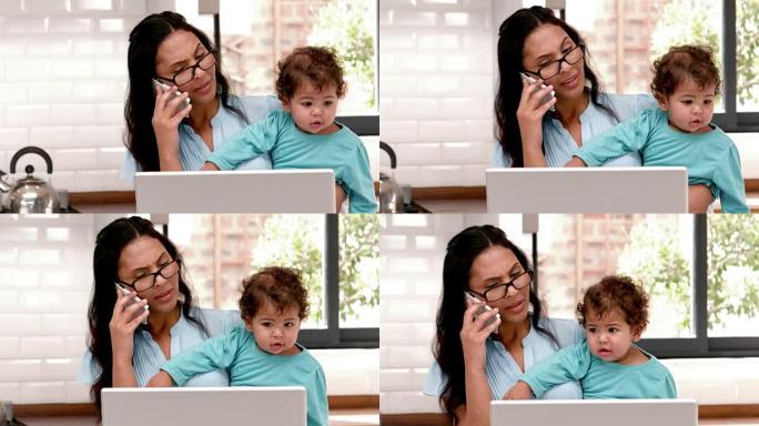 母亲在携带婴儿时使用笔记本电脑
