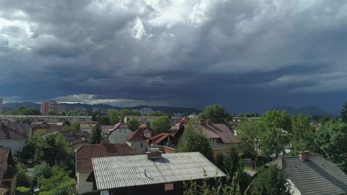空中: 美丽的绿色郊区城镇房屋屋顶上方的黑暗暴风雨云