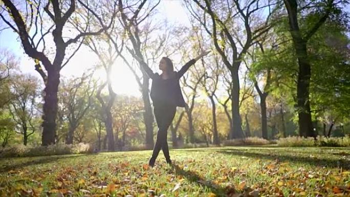 年轻漂亮的黑发女人享受阳光明媚的日子。秋天公园，落叶和树木。