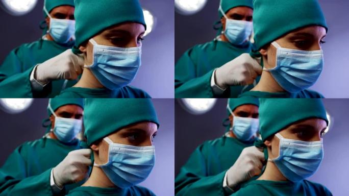 外科医生帮助护士在手术室系好外科口罩