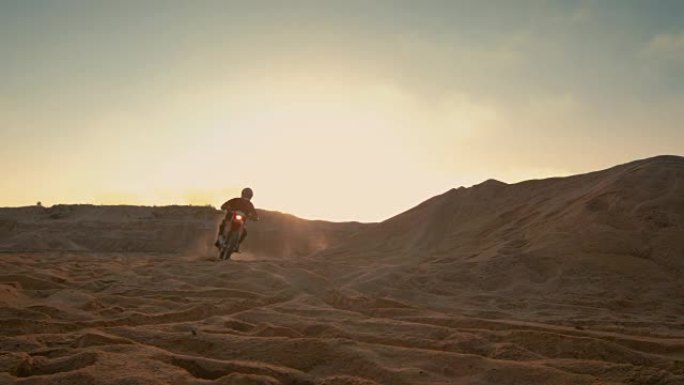 专业摩托车越野赛摩托车骑手在沙丘和越野车道上行驶。这是《日落》，赛道上布满了烟雾。
