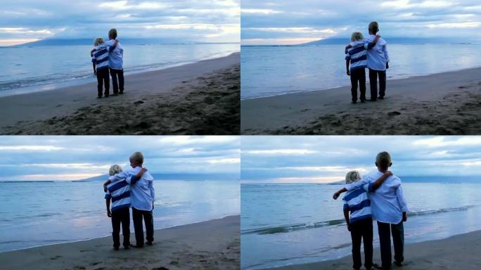 日落时，两个小男孩在海滩上摆姿势。