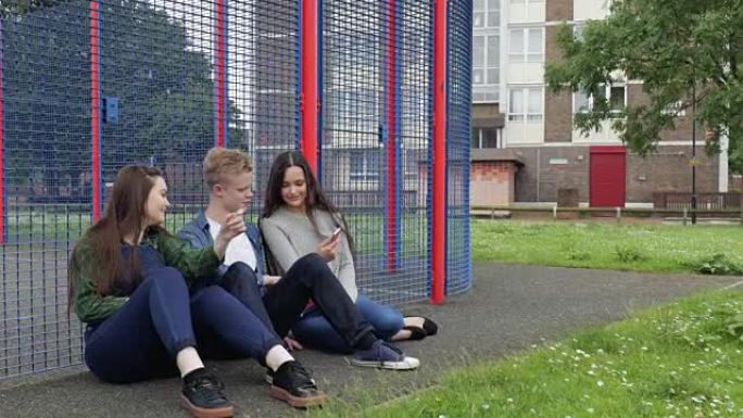 三个青少年在手机上在公园闲逛