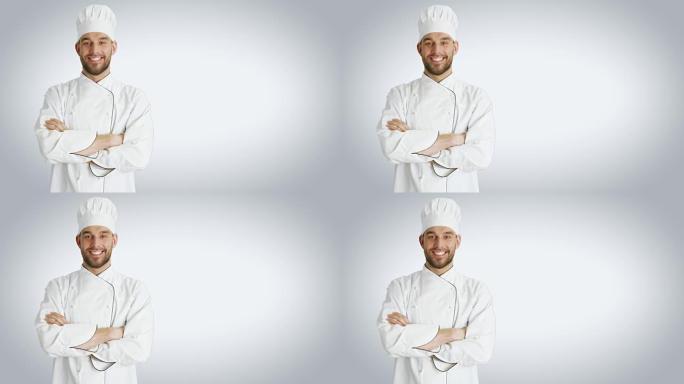 一个英俊的厨师交叉双臂微笑的镜头。以白色背景拍摄。