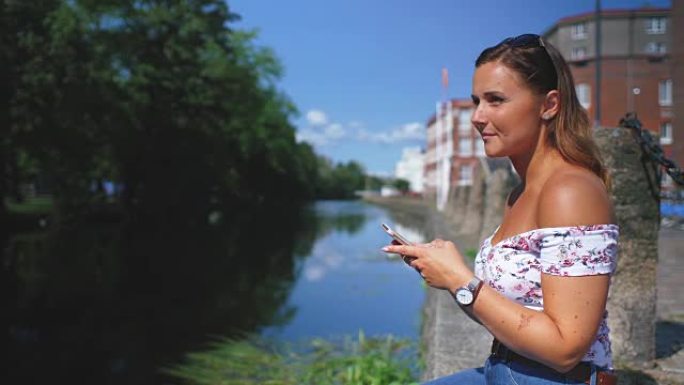 运河边使用手机的年轻女子