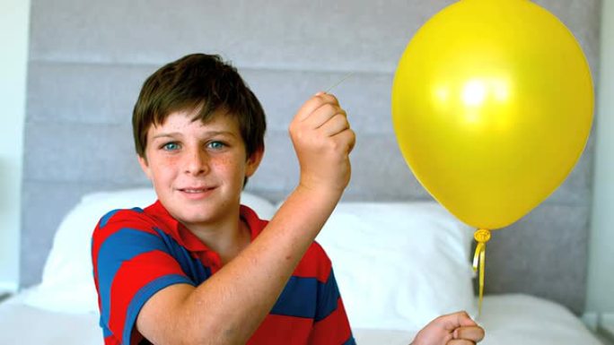 男孩在卧室里刺穿他的气球