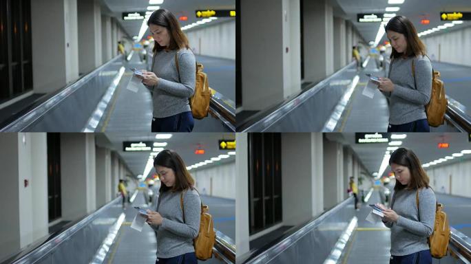 女乘客使用travolator前往登机口等待航班并通过手机在线办理登机手续