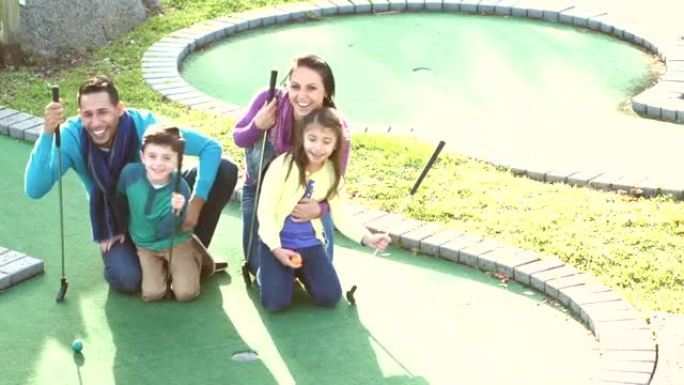 有两个孩子打迷你高尔夫球的家庭