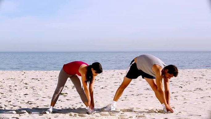 运动员和女运动员在海滩上伸展