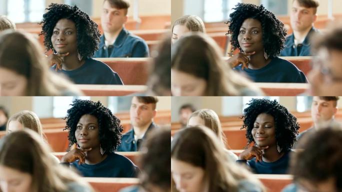 聪明美丽的年轻黑人女孩在充满多民族学生的教室里听讲座。浅景深。