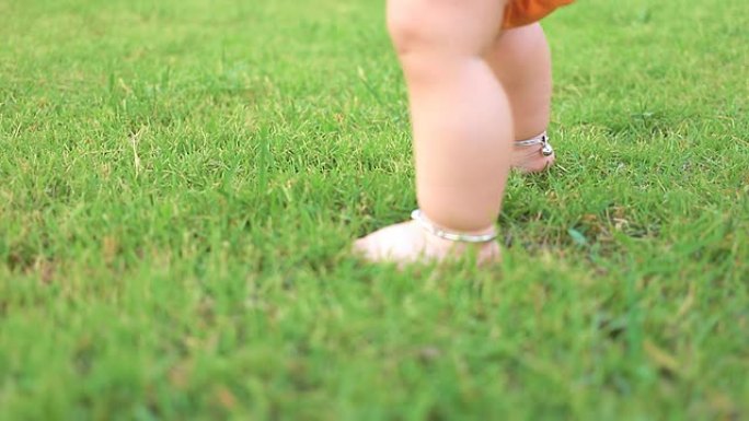 婴儿第一次踏上草地，慢动作，娃娃镜头。