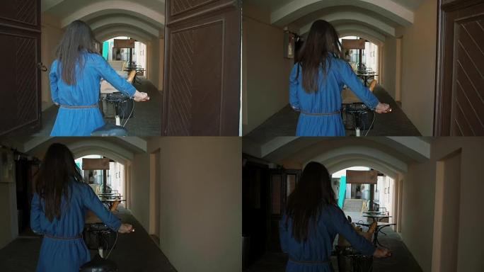 一个长发的黑发女孩骑着自行车走进老城区的老门，慢镜头，斯蒂德卡姆镜头