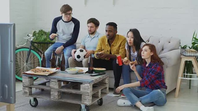 快乐朋友体育迷们一起在电视上看足球锦标赛在家吃披萨喝啤酒