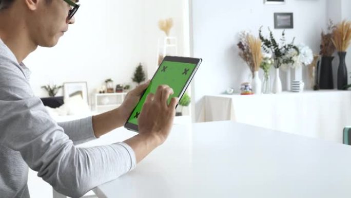 男人在家中使用带有绿色屏幕的数字平板电脑，垂直