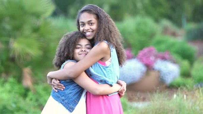 两个非裔美国人姐妹在花园里微笑