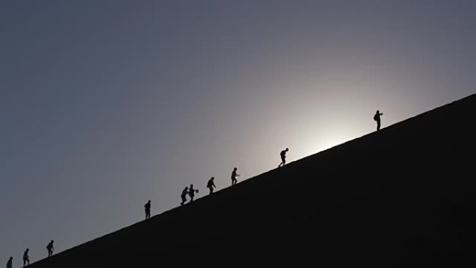 纳米布-瑙克鲁夫特国家公园背景下的太阳升起在沙丘上行走的游客的4k视图