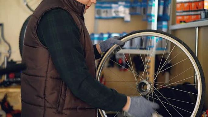 年轻的维修人员正在擦洗自行车车轮上的污垢，用一块织物清洁并用气雾剂处理。自行车维护和人的概念。