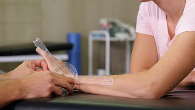 男性治疗师用测角仪测量女性患者的手