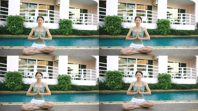 晴天，冷静的女人在酒店游泳池附近做瑜伽