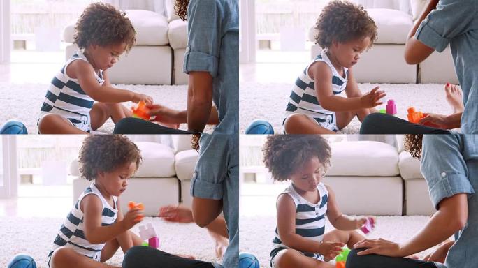 年轻的黑人女孩和她的妈妈在玩塑料砖