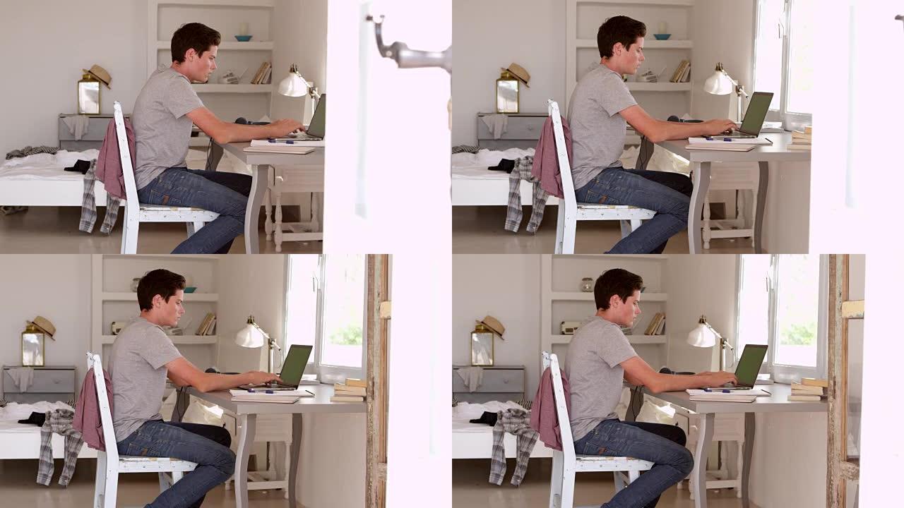 十几岁的男孩在卧室的桌子上使用计算机，在R3D上拍摄
