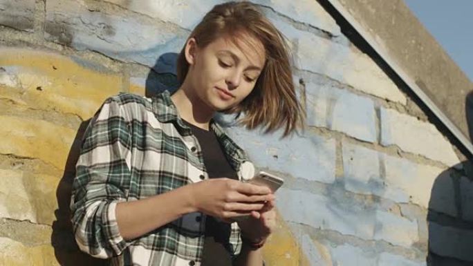 迷人的少女在城市环境中户外使用手机。