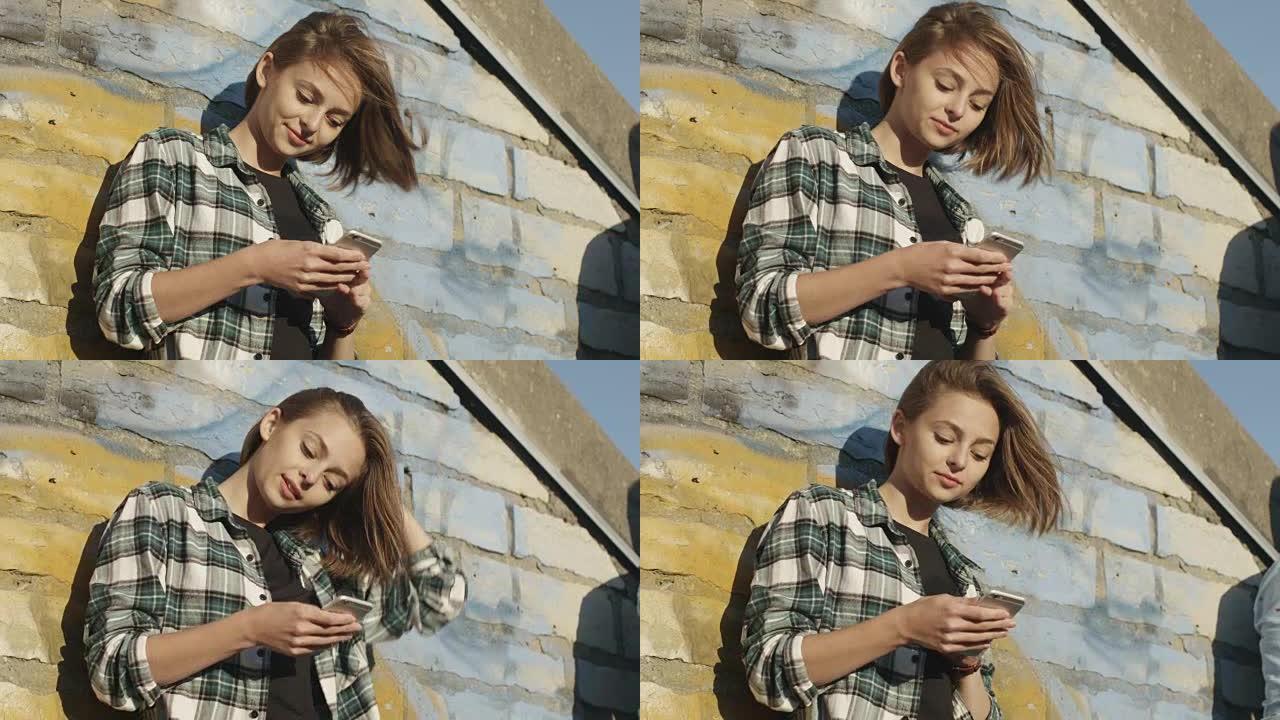 迷人的少女在城市环境中户外使用手机。