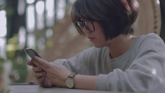 年轻的亚洲女性在咖啡馆使用智能手机。