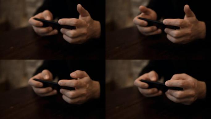 坐在餐桌旁的咖啡馆里，浏览互联网时，男性双手握着智能手机的特写镜头
