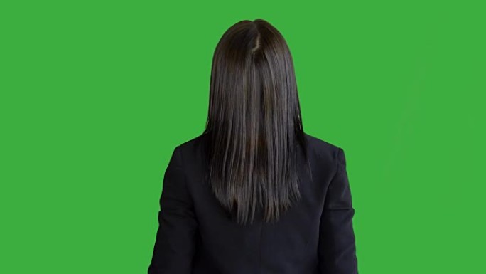 年轻迷人的黑发女人站在绿色屏幕背景下孤立。穿着西装的美丽职业女性肖像