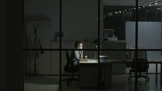 女人晚上在现代办公室工作