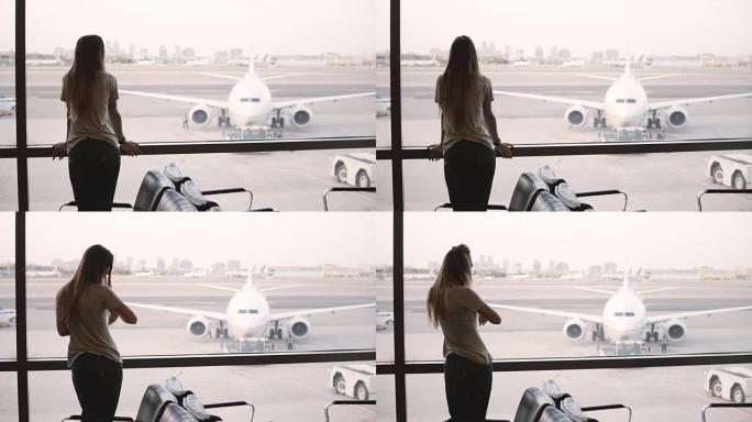 年轻的欧洲女商人站在机场候机厅的窗户上看，看着并使用智能手表