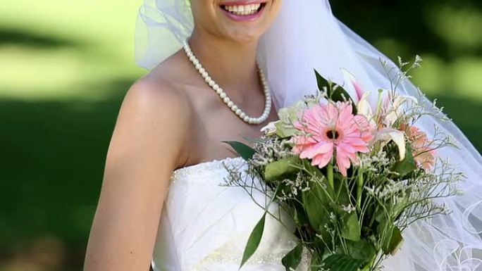 美丽的新娘在公园里对着镜头微笑