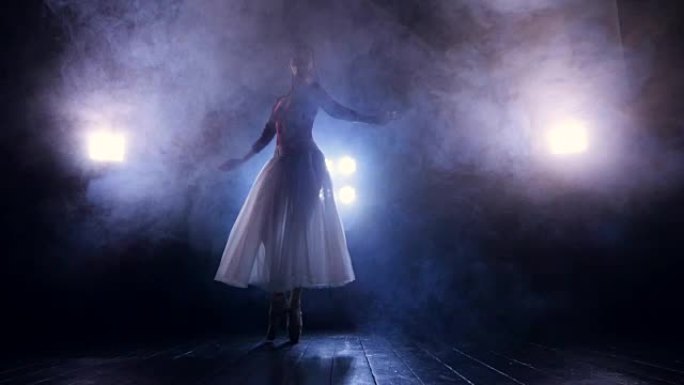 芭蕾舞演员在黑暗中慢慢转身。