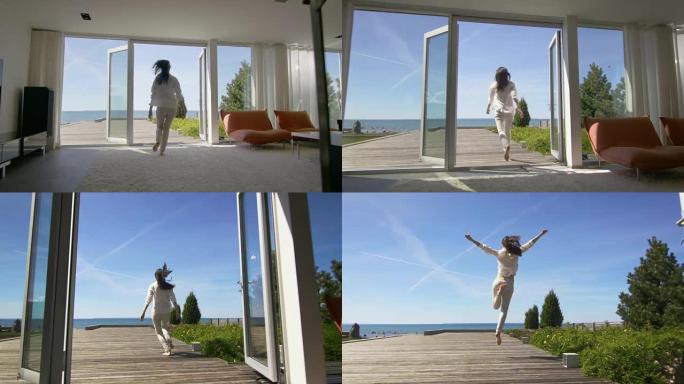 拍摄了一个美丽的年轻女子从她的房子跑到阳台上，可以看到海边的景色。