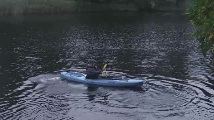 人在河里用桨转动皮划艇，然后飘走。