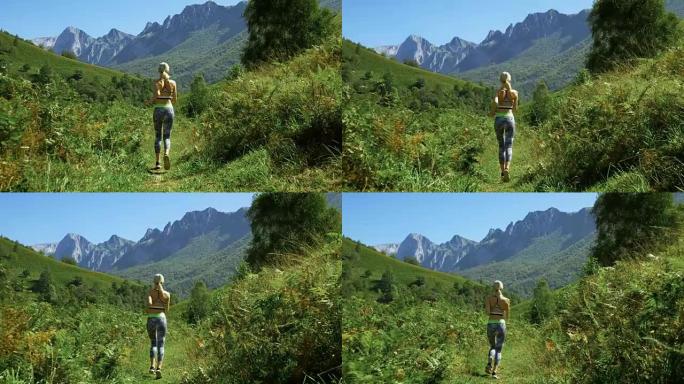 在美丽的健身女跑步者穿着运动服在小径上慢跑的镜头后，山景令人叹为观止。迷人的金发女孩和风景秀丽的大自